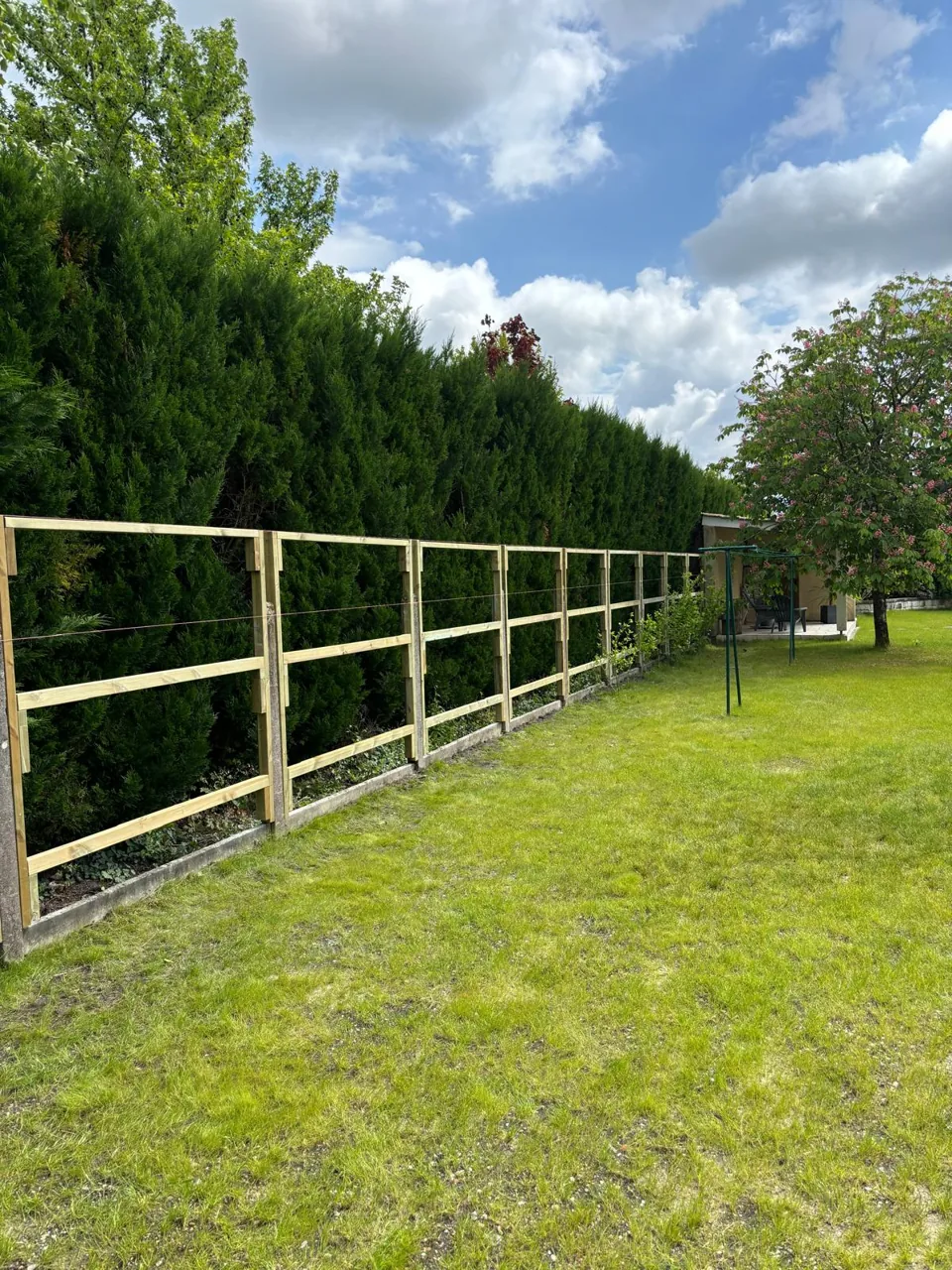 Ossature d&rsquo;une clôture bois en cours de pose